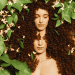 Stration of a woman with luscious, curly hair surrounded by tropical flowers and leaves, with Batana oil bottles and hair accessories subtly integrated into the scene